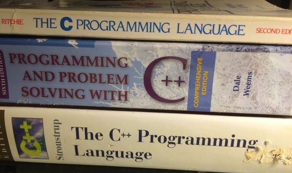 Three programming books piled up, dedicated to the C and C++ programming languages